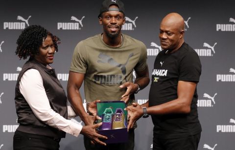 Jamaican athlete Usain Bolt shows his new and last running shoes with his parents, Jennifer, left, and Wellesley, right, during a press conference ahead of the World Athletics championships in London, Tuesday, Aug. 1, 2017. Sprint legend Bolt, a multiple Olympic and World Championship gold medallist, is set to retire after the World Championships in London, which begin on Friday Aug. 4.(AP Photo/Frank Augstein)