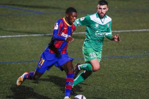 Barcelona's Ousmane Dembele, left, vies for the ball with Agus Medina during a Spanish Copa del Rey round of 32 soccer match between Cornella and FC Barcelona at the Nou Municipal stadium in Cornella, Spain, Thursday, Jan. 21, 2021. (AP Photo/Joan Monfort)