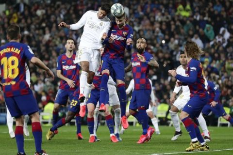 Real Madrid's Raphael Varane, center left, and Barcelona's Gerard Pique, center right, jump for the ball during the Spanish La Liga soccer match between Real Madrid and Barcelona at the Santiago Bernabeu stadium in Madrid, Spain, Sunday, March 1, 2020. (AP Photo/Manu Fernandez)