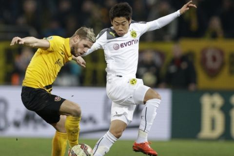 Dresden's Justin Eilers, left, and Dortmund's Shinji Kagawa from Japan challenge for the ball during the German soccer cup round of sixteen match between third division team Dynamo Dresden and first division team Borussia Dortmund in Dresden, Germany, Tuesday, March 3, 2015. (AP Photo/Michael Sohn)