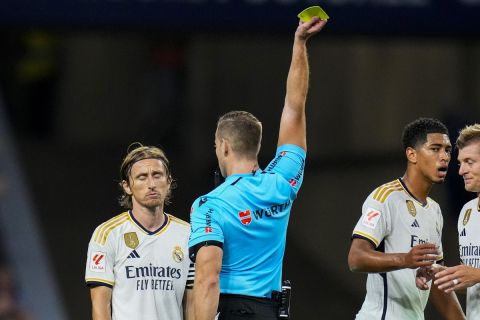 Real Madrid's Luka Modric, left, is shown a yellow card by referee Javier Alberola Rojas during the Spanish La Liga soccer match between Atletico Madrid and Real Madrid at Metropolitan stadium in Madrid, Sunday, Sept. 24, 2023. (AP Photo/Manu Fernandez)