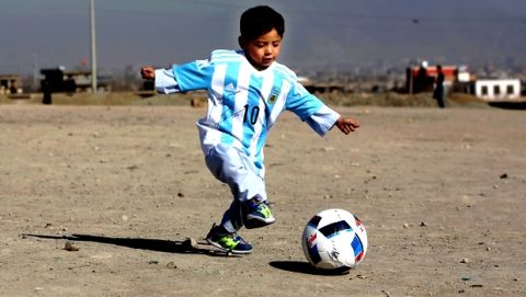 FILE - A Friday, Feb. 26, 2016 photo from files of Murtaza Ahmadi, a five-year-old Afghan Lionel Messi fan playing with a soccer ball during a photo opportunity as he wears a shirt signed by Messi, in Kabul, Afghanistan. Murtaza made a special trip from Afghanistan to Qatar, where Messi was with his Barcelona teammates to play a friendly match against Al Ahli on Tuesday, Dec. 13, 2016. In a meeting arranged by the organizing committee of the 2022 World Cup in Qatar, Messi held hands with Murtaza at the team hotel before picking up the boy and posing for photographs. Murtaza was wearing a Barcelona jersey.  (AP Photo/Rahmat Gul, File)