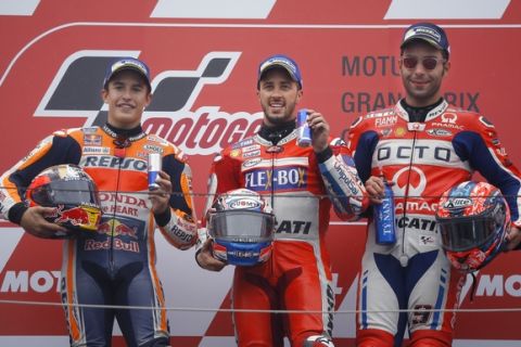 MotoGP winner Italy's Andrea Dovizioso, center, pose with Spain's Marc Marquez, left, and Danilo Petrucci of Italy during the award ceremony of the MotoGP Japanese Motorcycle Grand Prix at the Twin Ring Motegi circuit in Motegi, north of Tokyo, Sunday, Oct. 15, 2017. (AP Photo/Shizuo Kambayashi)