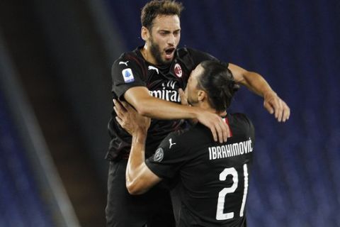 AC Milan's Hakan Calhanoglu, top, celebrates with his teammate Zlatan Ibrahimovic after scoring his side's opening goal during the Serie A soccer match between Lazio and AC Milan at the Rome Olympic stadium, Saturday, July 4, 2020. (AP Photo/Riccardo De Luca)