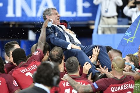 Portugal coach Fernando Santos is lifted by the players after winning the Euro 2016 final soccer match between Portugal and France at the Stade de France in Saint-Denis, north of Paris, Sunday, July 10, 2016. (AP Photo/Martin Meissner)