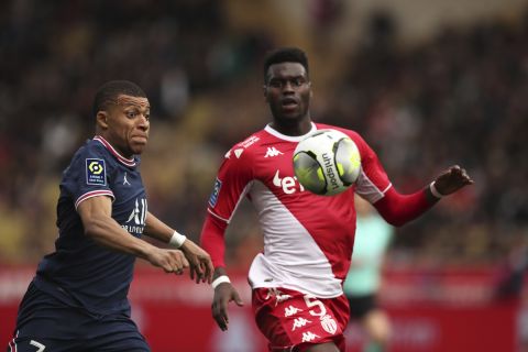 PSG's Kylian Mbappe, left, and Monaco's Benoit Badiashile vie for the ball during the French League One soccer match between Monaco and Paris Saint-Germain at the Stade Louis II in Monaco, Sunday, March 20, 2022. (AP Photo/Daniel Cole)