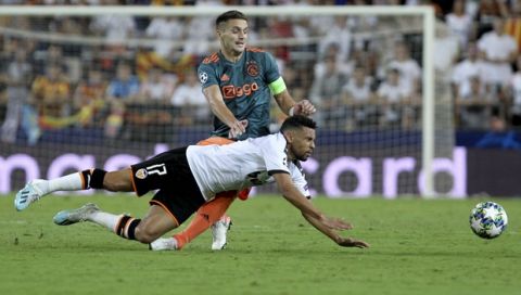 Valencia's Francis Coquelin is tackled by Ajax's Dusan Tadic during the Champions League group H soccer match between Valencia and Ajax, at the Mestalla stadium in Valencia, Wednesday, Oct.2, 2019. (AP Photo/Alberto Saiz)