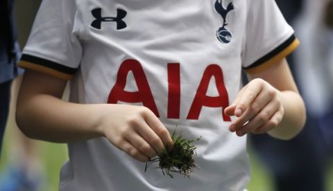 A young Tottenham fan takes a handful of turf as the pitch is invaded after the English Premier League soccer match between Tottenham Hotspur and Manchester United at White Hart Lane stadium in London, Sunday, May 14, 2017. It was the last Spurs match at the old stadium, a new stadium is being built on the site. (AP Photo/Frank Augstein)