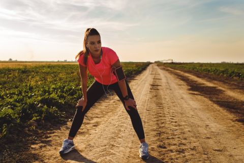 Athletic woman taking brake after running on rural road.