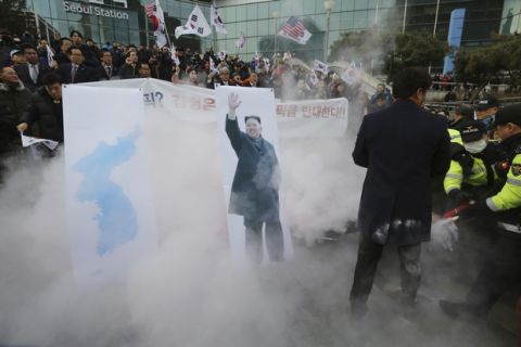 South Korean protesters try to burn a portrait of North Korean leader Kim Jong Un as police officers spray fire extinguishers during a rally against a visit of North Korean Hyon Song Wol, head of a North Korean art troupe, in front of Seoul Railway Station in Seoul, South Korea, Monday, Jan. 22, 2018. Dozens of conservative activists have attempted to burn a large photo of North Korean leader Kim Jong Un as the head of the North's hugely popular girl band passed by them at a Seoul railway station. (AP Photo/Ahn Young-joon)