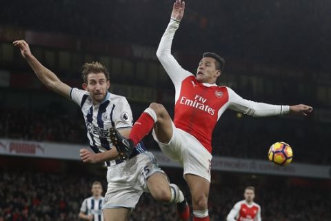 Arsenal's Alexis Sanchez, right, vies for the ball with West Brom's Craig Dawson during the English Premier League soccer match between Arsenal and West Bromwich Albion at Emirates stadium in London, Monday, Dec. 26, 2016. (AP Photo/Kirsty Wigglesworth)