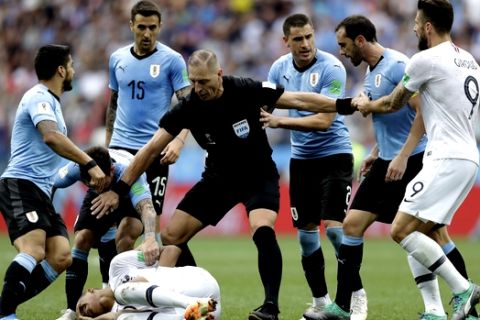 Uruguay players protest to referee Nestor Pitana of Argentina that France's Kylian Mbappe, on the ground, is overreacting after taking a dive during the quarterfinal match between Uruguay and France at the 2018 soccer World Cup in the Nizhny Novgorod Stadium, in Nizhny Novgorod, Russia, Friday, July 6, 2018. (AP Photo/Natacha Pisarenko)