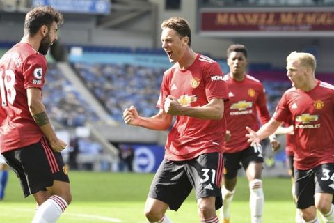 Manchester United's Bruno Fernandes, left, celebrates with teammates after he scores his sides third goal from the penalty spot during the English Premier League soccer match between Brighton Hove Albion and Manchester United in Brighton, England, Saturday, Sept. 26, 2020. (Glyn Kirk/Pool via AP)