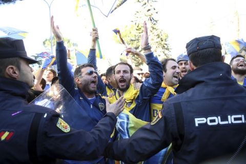 Spanish police officers hold back Boca Juniors supporters cheering the players arriving at the team hotel in Madrid Saturday, Dec. 8, 2018. The Copa Libertadores Final between River Plate and Boca Juniors will be played on Dec. 9 in Madrid, Spain, at Real Madrid's stadium. (AP Photo/Andrea Comas)