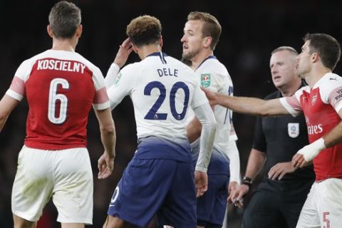 Tottenham's Dele Alli, second from left, reacts after a bottle was thrown at him from the stands during the English League Cup quarter final soccer match between Arsenal and Tottenham Hotspur at the Emirates stadium in London, Wednesday, Dec. 19, 2018. (AP Photo/Frank Augstein)