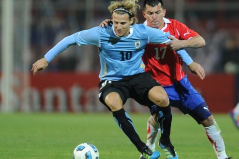 Uruguayan forward Diego Forlan (L) is marked by Chilean midfielder Gary Medel during the 2011 Copa America Group C first round football match against Uruguay held at the Malvinas Argentinas stadium in Mendoza, 1058 Km west of Buenos Aires, on July 8, 2011.     AFP PHOTO / Ronaldo Schemidt (Photo credit should read Ronaldo Schemidt/AFP/Getty Images)