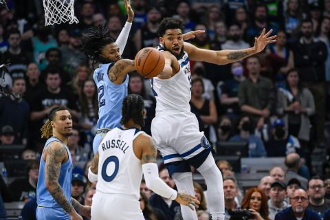 Minnesota Timberwolves center Karl-Anthony Towns, right, passes back to Timberwolves guard D'Angelo Russell as Memphis Grizzlies guard Ja Morant, second from left, defends and Grizzlies forward Brandon Clark, left, looks on during the first half in Game 4 of an NBA basketball first-round playoff series Saturday, April 23, 2022, in Minneapolis. (AP Photo/Craig Lassig)