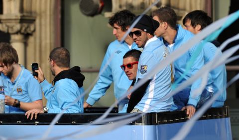 Manchester City's Argentinian forward Carlos Tevez sits with his teammates on an open topped bus as they celebrate becoming English Premier League champions in a parade leaving from Mancheter Town Hall in Manchester, northwest England, on May 14, 2012. Manchester City beat their rivals Manchester United on goal difference to be crowned champions on the final day of the season with a 3-2 victory over Queens Park Rangers. AFP PHOTO/PAUL ELLISPAUL ELLIS/AFP/GettyImages