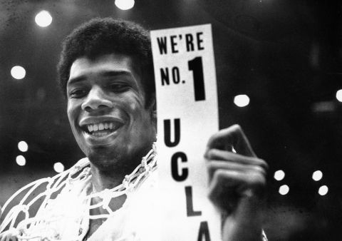 FILE - In this March 23, 1968, file photo, UCLA's Lew Alcindor, with the basket netting draped over his shoulders, holds a sign just after leading UCLA to the NCAA basketball championship in Los Angeles on March 23, 1968.  Muhammad Alis actions influenced others. Alcindor boycotted the 1968 Summer Olympics. boycotted the 1968 Summer Olympics. After winning his first NBA championship in 1971, he took the Muslim name Kareem Abdul-Jabbar. (AP Photo/File)