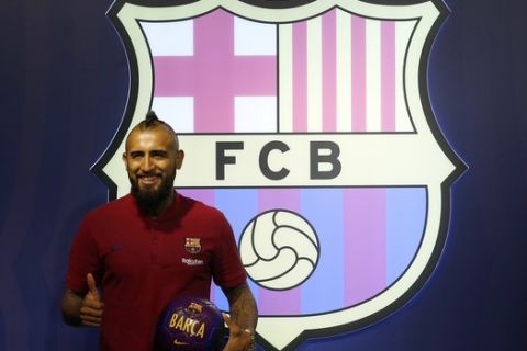 Chilean soccer player Arturo Vidal poses for the media in a FC Barcelona's shop next to Camp Nou stadium in Barcelona, Spain, Sunday, Aug. 5, 2018. Vidal has agreed a three-year contract at the Nou Camp. (AP Photo/Manu Fernandez)