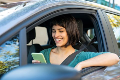 Portrait of smiling woman inside car during daytime