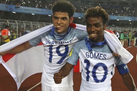England's Morgan Gibbs White, left, and England's Angel Gomes bite their medals as they celebrates after their team won the FIFA U-17 World Cup in Kolkata, India, Saturday, Oct. 28, 2017. (AP Photo/Anupam Nath)