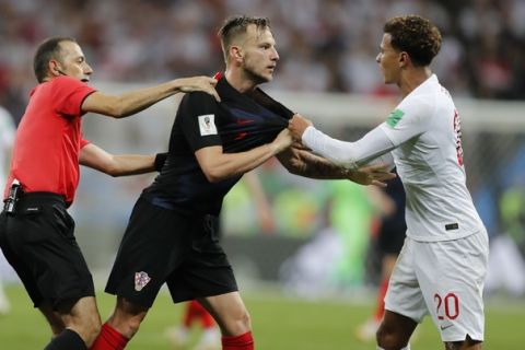 Croatia's Ivan Rakitic, center, and England's Dele Alli, right, are separated by referee Cuneyt Cakir from Turkey during the semifinal match between Croatia and England at the 2018 soccer World Cup in the Luzhniki Stadium in Moscow, Russia, Wednesday, July 11, 2018. (AP Photo/Frank Augstein)