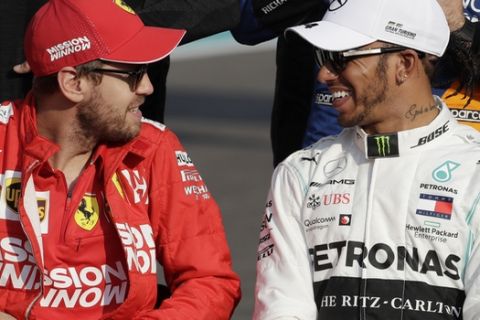 Mercedes driver Lewis Hamilton of Britain, right, smiles to Ferrari driver Sebastian Vettel of Germany during the end season driver's picture at the Emirates Formula One Grand Prix, at the Yas Marina racetrack in Abu Dhabi, United Arab Emirates, Sunday, Dec.1, 2019. (AP Photo/Luca Bruno)