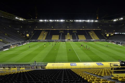 FILE - Players warm up in a stadium without fans prior to the the German Bundesliga soccer match between Borussia Dortmund and Bayern Munich in Dortmund, Germany, Saturday, Nov. 7, 2020. One year late, it is unclear how many fans will be allowed for the Bundesliga clash between Dortmund and Bayern on Saturday, as the BVB has precautionary cancelled all tickets for the match due to the coronavirus pandemic. (AP Photo/Martin Meissner, File)