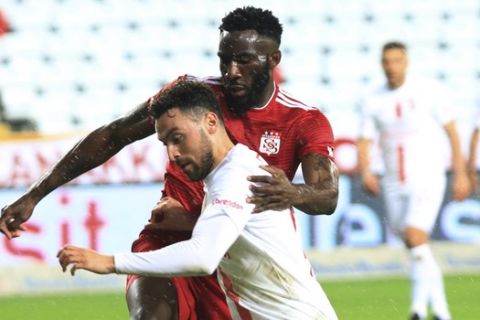 Antalyaspor's Sinan Gumus, right, tries to dribble past Sivasspor's Aaron Christopher Billy Ondele Appindangoye, during a Turkish Super League soccer match between Antalyaspor and Sivasspor in Antalya, Turkey, Monday, March 16, 2020. The match was played without spectators because of the coronavirus outbreak. For most people, the new coronavirus causes only mild or moderate symptoms. For some it can cause more severe illness. (AP Photo)
