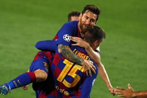 Barcelona's Clement Lenglet is embraced by Barcelona's Lionel Messi after scoring the opening goal during the Champions League round of 16, second leg soccer match between Barcelona and Napoli at the Camp Nou Stadium in Barcelona, Spain, Saturday, Aug. 8, 2020. (AP Photo/Joan Monfort)