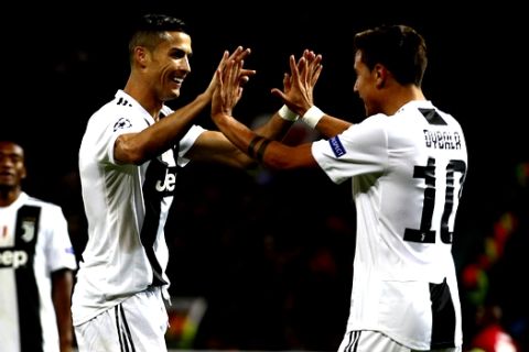 Juventus forward Paulo Dybala, right, celebrates with Juventus forward Cristiano Ronaldo after scoring the opening goal during the Champions League group H soccer match between Manchester United and Juventus at Old Trafford, Manchester, England, Tuesday, Oct. 23, 2018. (AP Photo/Dave Thompson)