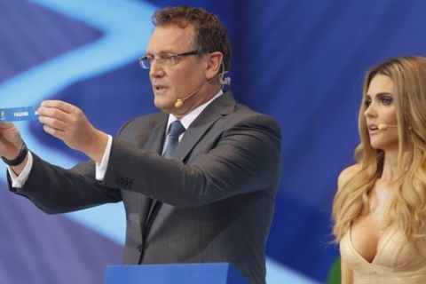 FIFA Secretary General Jerome Valcke holds up the slip showing "Uruguay" next to presenter Fernanda Lima during the draw for the 2014 World Cup at the Costa do Sauipe resort in Sao Joao da Mata, Bahia state, December 6, 2013. The 2014 World Cup finals will be held in Brazil from June 12 through July 13.  REUTERS/Paulo Whitaker (BRAZIL  - Tags: SPORT SOCCER SPORT SOCCER WORLD CUP)  