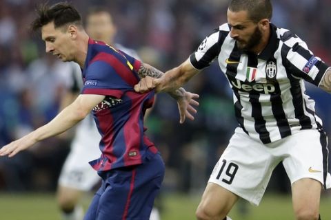 Juventus' Leonardo Bonucci, right, holds the shirt of Barcelona's Lionel Messi during the Champions League final soccer match between Juventus Turin and FC Barcelona at the Olympic stadium in Berlin Saturday, June 6, 2015. (AP Photo/Michael Probst)