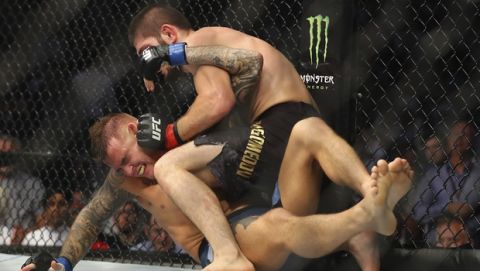 Russian UFC fighter Khabib Nurmagomedov, top, fights with UFC fighter Dustin Poirier, of Lafayette, La., during Lightweight title mixed martial arts bout at UFC 242, in Yas Mall in Abu Dhabi, United Arab Emirates, Saturday , Sept.7 2019. (AP Photo/ Mahmoud Khaled)