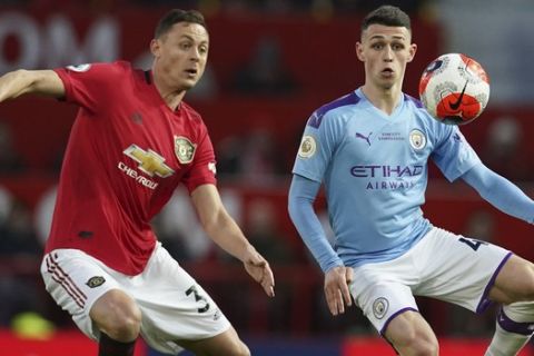 Manchester City's Phil Foden, right, and Manchester United's Nemanja Matic compete for the ball during the English Premier League soccer match between Manchester United and Manchester City at Old Trafford in Manchester, England, Sunday, March 8, 2020. (AP Photo/Dave Thompson)