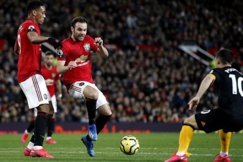 Manchester United's Anthony Martial, left, and Juan Mata vie for the ball during the English Premier League soccer match between Manchester United and Wolverhampton Wanderers, at Old Trafford, in Manchester, England, Saturday, Feb. 1, 2020. (Martin Rickett/PA via AP)