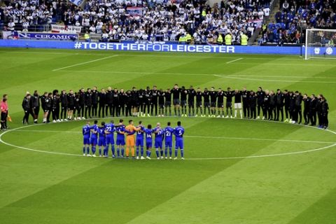 Leicester City players and staff stand with Cardiff City players and match officials during a minute's silence in memory of the victims of the Leicester City helicopter crash which included Chairman Vichai Srivaddhanaprabha during the English Premier League soccer match between Cardiff City and Leicester City at the Cardiff City Stadium, Cardiff. Wales. Saturday Nov. 3, 2018. (Simon Galloway/PA via AP)