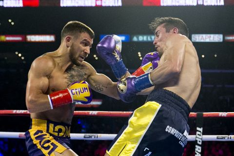 FILE - In this April 12, 2019, file photo, Vasiliy Lomachenko, left, from Ukraine, hits Anthony Crolla, from Britain, during a WBA and WBO lightweight title boxing match in Los Angeles. In ordinary times Vasiliy Lomachenko and Teofimo Lopez would be the fight of the fall, a lightweight title match about as compelling as it gets in the boxing world these days. Instead of a big crowd, the only fans at the MGM Grand conference center will be a few hundred sponsors and first responders with special invites. And, instead of pay-per-view, the fight will be televised live on ESPN, guaranteeing a larger audience than a pay-per-view even if the money isnt nearly the same. (AP Photo/Damian Dovarganes, File)