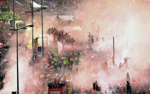 Smoke from flares engulf the scene as Liverpool soccer team ride an open top bus during the Champions League Cup Winners Parade through the streets of Liverpool, England, Sunday June 2, 2019.  Liverpool is champion of Europe for a sixth time after beating Tottenham 2-0 in the Champions League final played in Madrid Saturday. (Danny Lawson/PA via AP)
