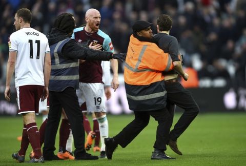 A Pitch invader is seized by security staff during the English Premier League soccer match between Burnley and West Ham at the Olympic London Stadium in London, Saturday, March 10, 2018. (Daniel Hambury/PA via AP)