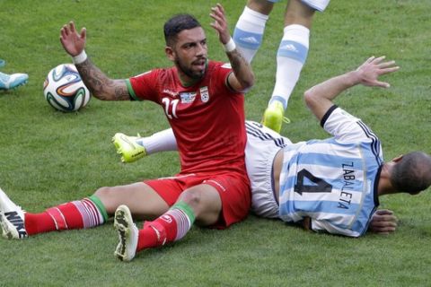 Iran's Ashkan Dejagah protests after being tackled by Argentina's Pablo Zabaleta, right, during the group F World Cup soccer match between Argentina and Iran at the Mineirao Stadium in Belo Horizonte, Brazil, Saturday, June 21, 2014. (AP Photo/Sergei Grits)