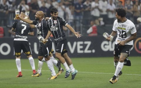 Corinthians players carry drinks as they celebrate winning the Brasileirao soccer championship title, after their match with Fluminense in Sao Paulo, Brazil, Wednesday, Nov. 15, 2017. Corinthians won 3-1. (AP Photo/Andre Penner)