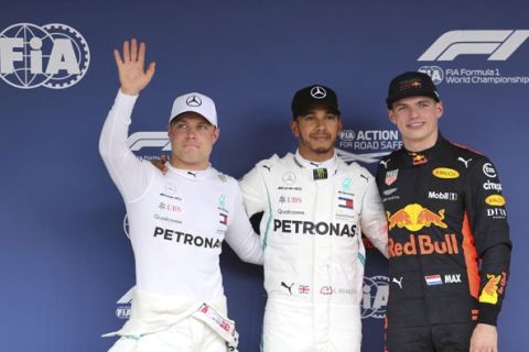 Mercedes driver Lewis Hamilton, center, of Britain poses with teammate Valtteri Bottas, left, of Finland and Red Bull driver Max Verstappen of the Netherlands after claiming pole position for the Japanese Grand Prix at the Suzuka Circuit in Suzuka, central Japan, Saturday, Oct. 6, 2018. Bottas finished second and Verstappen was third. (AP Photo/Toru Takahashi)