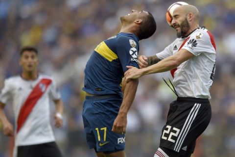 In this Nov. 11, 2018 photo, Ramón Abila of Argentina's Boca Juniors, center, heads the ball with Javier Pinola of Argentina's River Plate during the first leg soccer match of the Copa Libertadores final in Buenos Aires, Argentina. The match ended in a 2-2 draw. (AP Photo/Gustavo Garello)