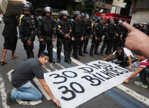 RIO DE JANEIRO, BRAZIL - JUNE 12:  Protestors place a sign in front of police during an anti-World Cup demonstration in the Copacabana section on June 12, 2014 in Rio de Janeiro, Brazil. This is the first day of World Cup play.  (Photo by Joe Raedle/Getty Images)
