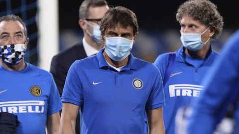 Inter Milan coach Antonio Conte, center, wearing a face mask, enters the pitch prior to the Italian Cup second leg semifinal soccer match between Napoli and Inter Milan, at the Naples San Paolo Stadium, Italy, Saturday, June 13, 2020. The match is being played without spectators because of the COVID-19 restriction measures. (Cafaro/LaPresse via AP)
