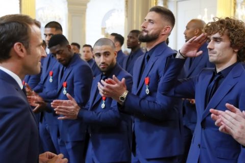 France's soccer player Antoine Griezmann, right, salutes prior to be awarded of the Legion d'Honneur (Officer of the Legion of Honor) medal by French president Emmanuel Macron during a ceremony at the Elysee Palace in Paris, Tuesday, June 4, 2019. (AP Photo/Francois Mori, pool)