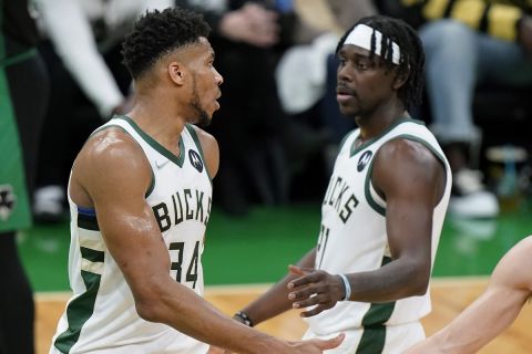 Milwaukee Bucks forward Giannis Antetokounmpo, left, of Greece, celebrates with guards Jrue Holiday, center, and Grayson Allen, right, after making a free throw in the second half of Game 1 in the second round of the NBA Eastern Conference playoff series against the Boston Celtics, Sunday, May 1, 2022, in Boston. (AP Photo/Steven Senne)