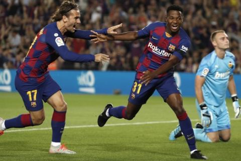 Barcelona's Ansu Fati, centre, celebrates with teammate Barcelona's Antoine Griezmann, left, after scoring the opening goal during the Spanish La Liga soccer match between FC Barcelona and Valencia CF at the Camp Nou stadium in Barcelona, Spain, Saturday, Sep. 14, 2019. (AP Photo/Joan Monfort)